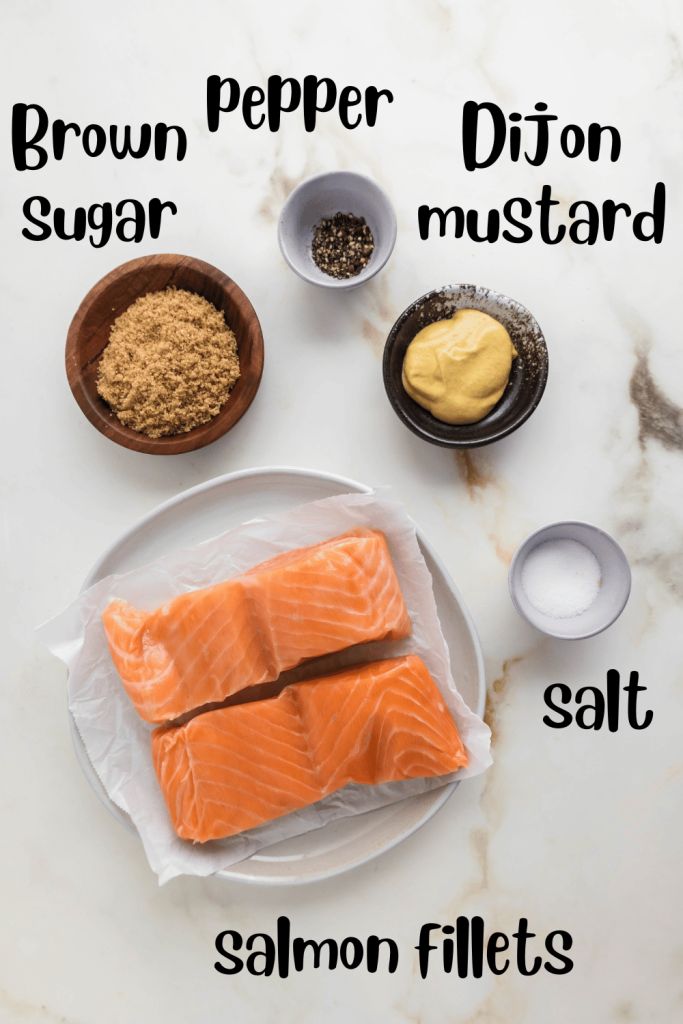 salmon fillets on a plate with spices and seasoning in bowls next to them