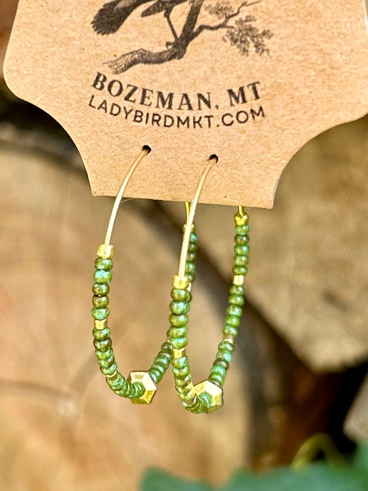 Introducing our vibrant Boho Seed Bead Hoop Earrings! These are the perfect blend of bohemian charm and contemporary style, featuring a delicate gold-colored hoop adorned with hunter-green earth-toned Czech glass seed beads with an eye-catching gold centerpiece. The beads, available in a kaleidoscope of hues, create an eye-catching mosaic.Our Boho Seed Bead Hoop Earrings are also incredibly lightweight, ensuring optimal comfort. Whether you're heading to a music festival, a beach getaway, or simply want to add a pop of color to your everyday ensemble, these earrings are the perfect choice. They effortlessly elevate any outfit, from casual boho-chic looks to more elegant and sophisticated styles. Green Hoop Beaded Earrings, Green Hoop Beaded Earrings With Ear Wire, Green Beaded Hoop Earrings With Ear Wire, Green Bohemian Beaded Hoop Earrings, Nickel Free Green Small Hoop Beaded Earrings, Green Beaded Hoop Earrings For Summer, Nickel-free Small Hoop Green Beaded Earrings, Green Nickel-free Small Hoop Beaded Earrings, Summer Beaded Green Hoop Earrings