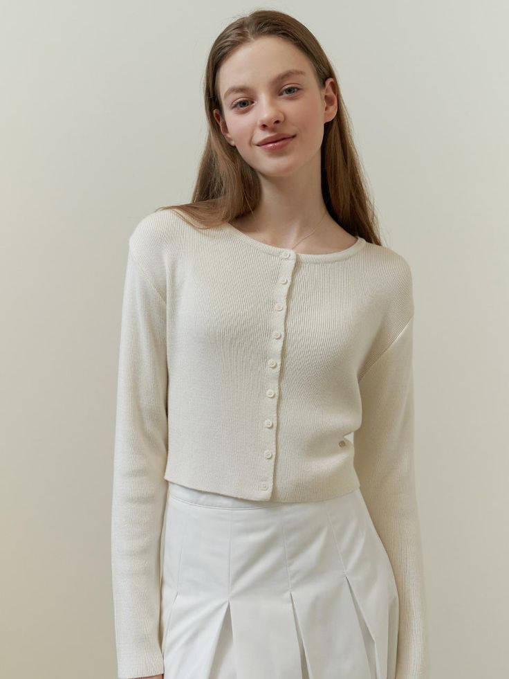 This is a classic cardigan with a simple, chic design. It has a round neckline and a full button placket with small, evenly spaced buttons. The cardigan is designed with a fitted silhouette and long sleeves, suggesting a snug and comfortable fit. A small, discreet logo or emblem is visible on the front, indicating a touch of branding.- Round neckline and full button placket are key features.- Fitted silhouette with long sleeves.- A subtle logo embellishes the front of the cardigan. Classic Fine Knit Spring Cardigan, Elegant Crew Neck Outerwear With Button Closure, Elegant Crew Neck Outerwear With Buttons, Chic Crew Neck Cardigan With Buttons, Chic Cardigan With Button Closure, Chic Solid Cardigan With Button Closure, Elegant Fitted Crew Neck Cardigan, Spring Crew Neck Cardigan With Button Cuffs, Chic Cardigan With Button Closure And Crew Neck