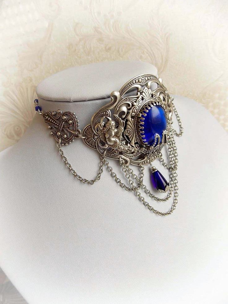 "Gothic inspired choker 'The Downfall' by Midnight Vision Jewelry This choker is elegant and richly decorated. I created it with a sapphire blue Czech glass jewel in crown shaped frame and base in antiqued finish. There are two cherubs on both sides, under of them are chains which increases it to be more elegant. The choker follows the curve of your neck and beautifully embraces it. This a statement piece to wear for any special events. Please choose the length for a perfect fit(12-14\" or 14-16 Victorian Choker, Gothic Choker, Elegant Choker, Goth Choker, Blue Choker, Gothic Chokers, Bridal Choker, Gothic Victorian, Victorian Gothic