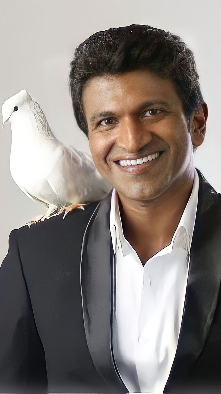 a man in a tuxedo holding a white bird on his shoulder and smiling at the camera