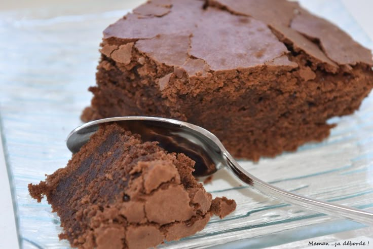 a piece of chocolate cake on a glass plate with a spoon