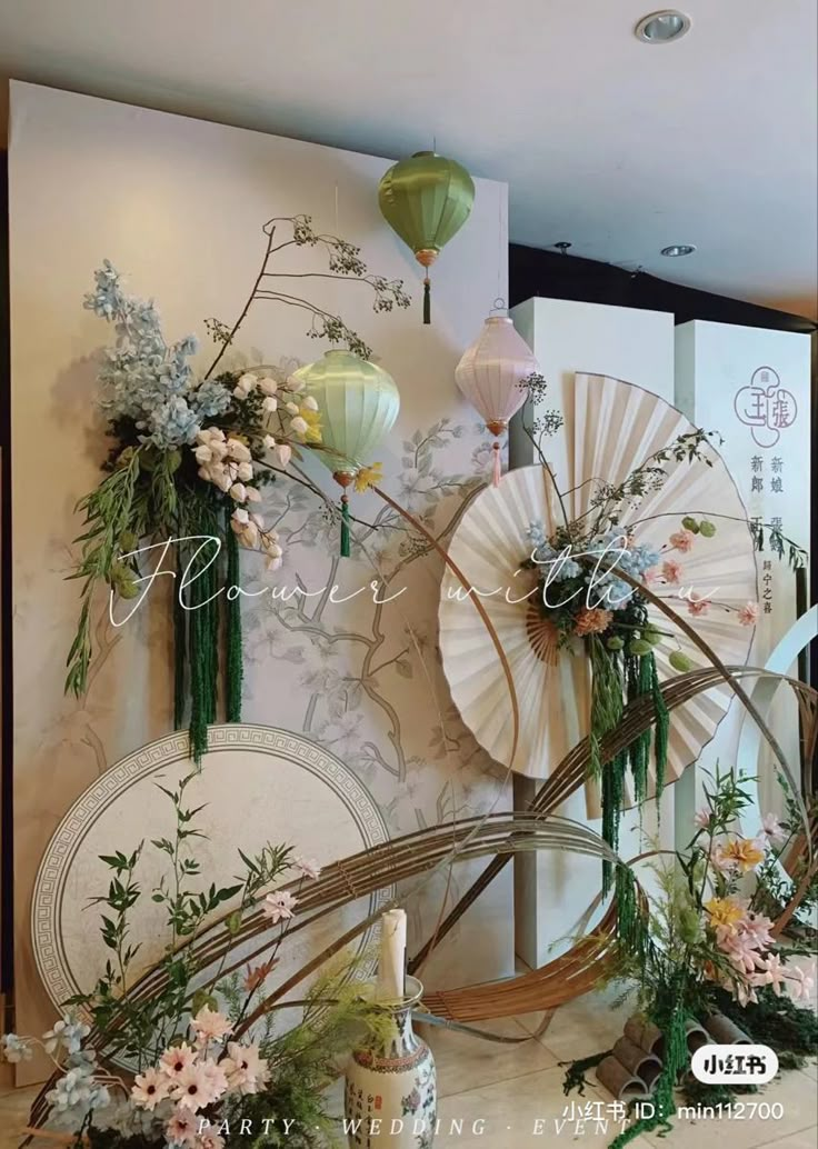 an arrangement of flowers and paper lanterns are displayed on the wall in front of a mirror