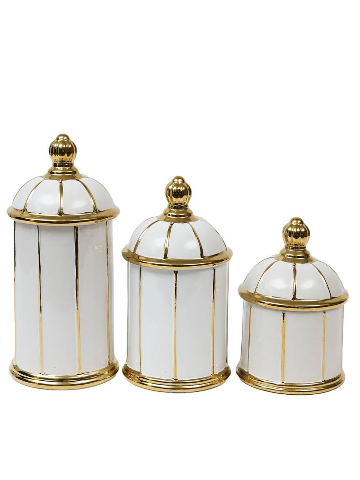 three white and gold canisters with lids