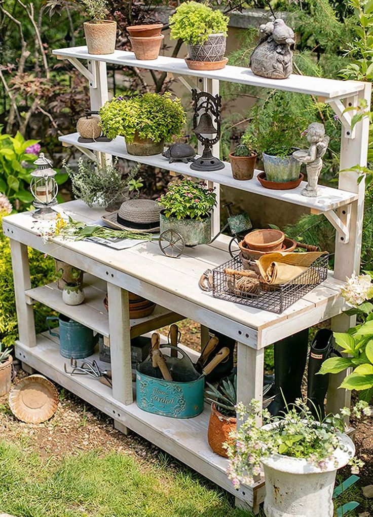 an outdoor garden area with potted plants and pots on top of a shelf in the grass