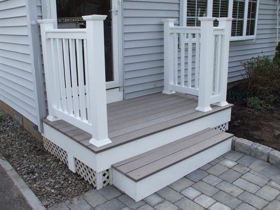 a white porch with steps leading up to the front door and side entryway area