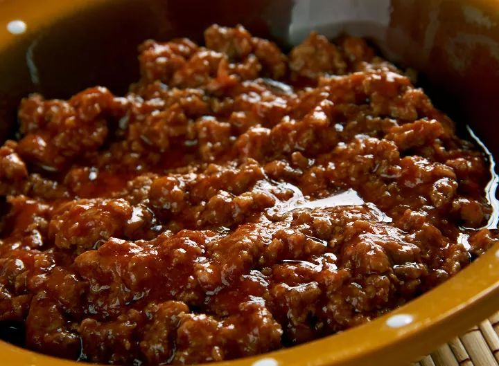 a brown bowl filled with meat and sauce