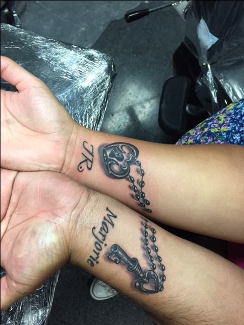 two people holding hands with tattoos on their arms and the other hand has a key