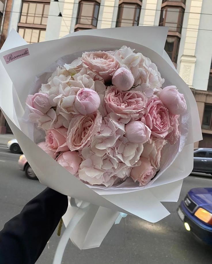 a person holding a bouquet of pink flowers