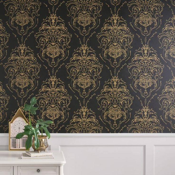 a white table with a plant on top of it next to a black wallpaper