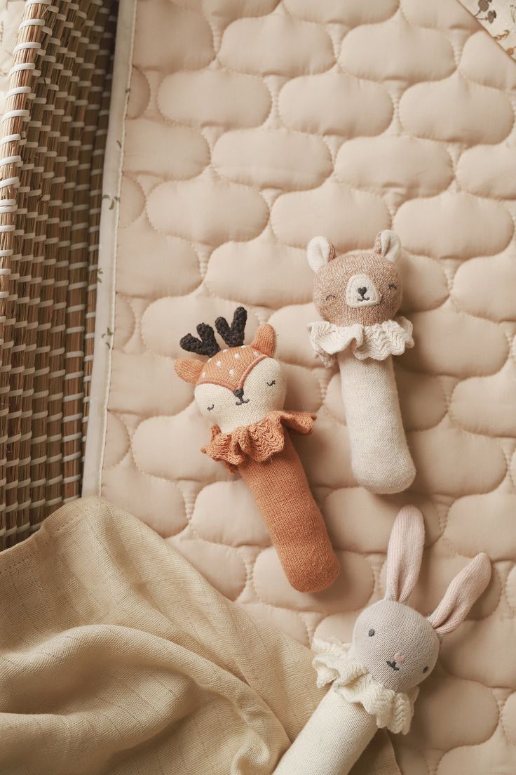 three little stuffed animals are laying on the mattresses next to each other and one is wearing a sweater