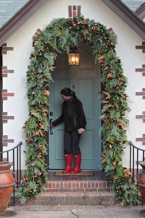 a man standing in front of a blue door wearing red boots and holding his hand out