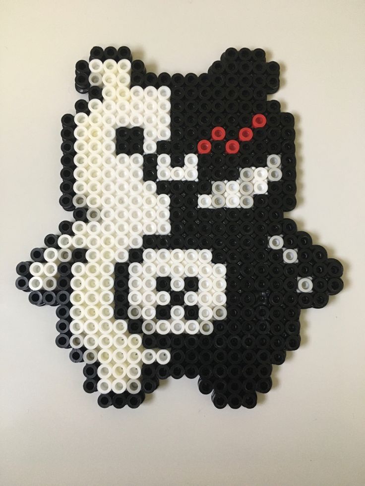 a black and white cat with red eyes made out of legos on a wall