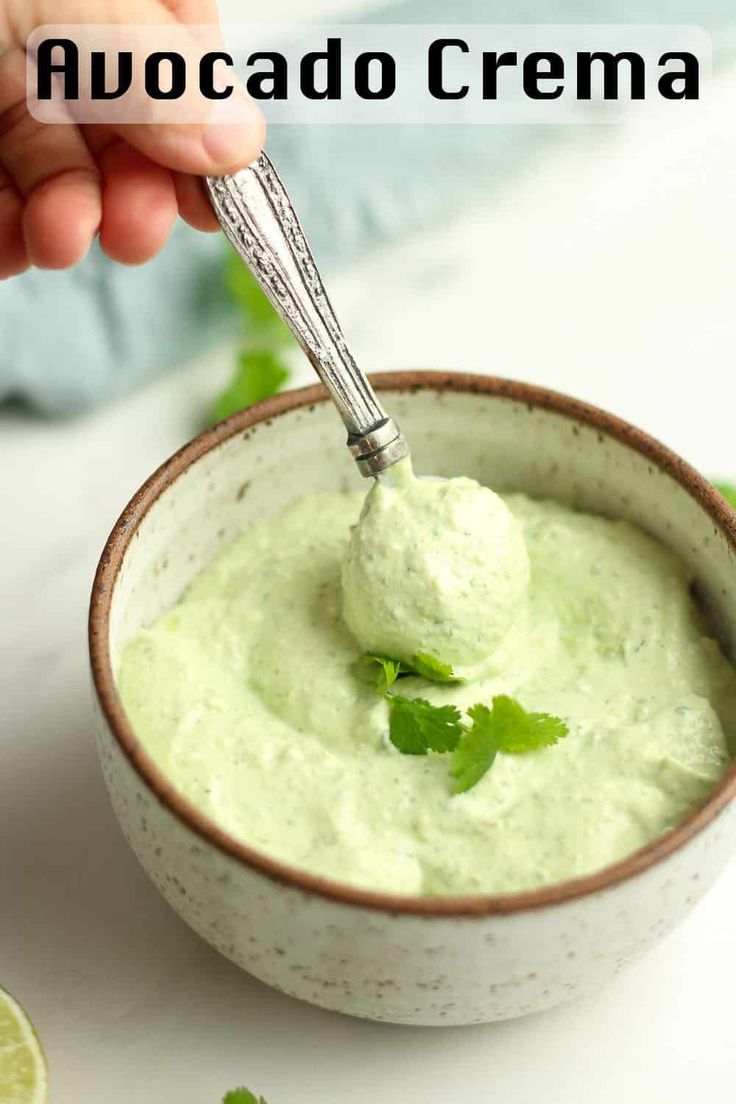 a person dipping guacamole into a bowl with limes around it and the text overlay reads, how to make avocado crema