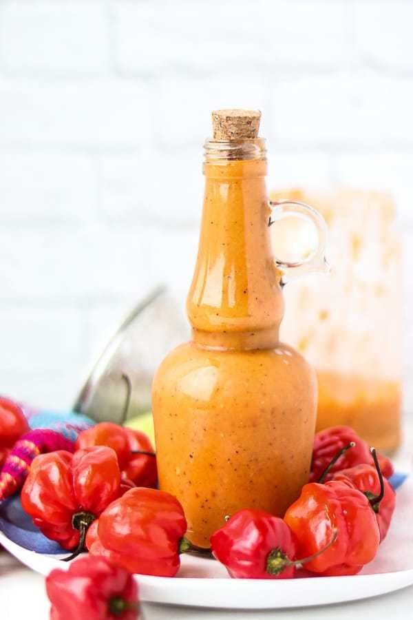 a bottle of mustard sitting on top of a plate next to red peppers and other vegetables