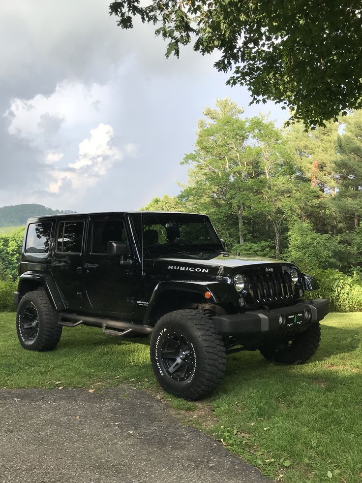 a black jeep is parked in the grass