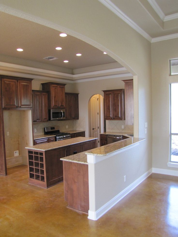 an empty kitchen with wooden cabinets and marble counter tops