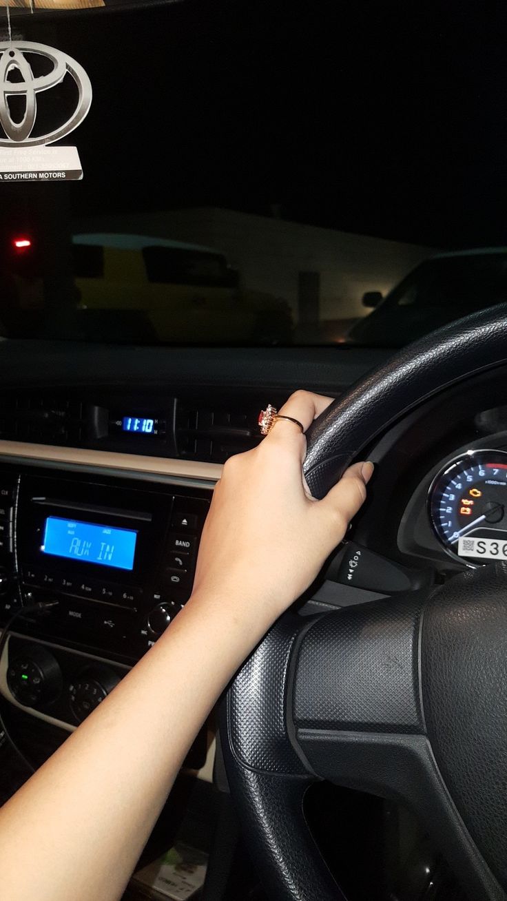 a person driving a car at night with their hand on the steering wheel