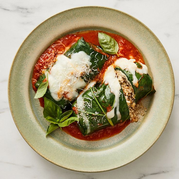 a bowl filled with spinach covered in sauce and cheese