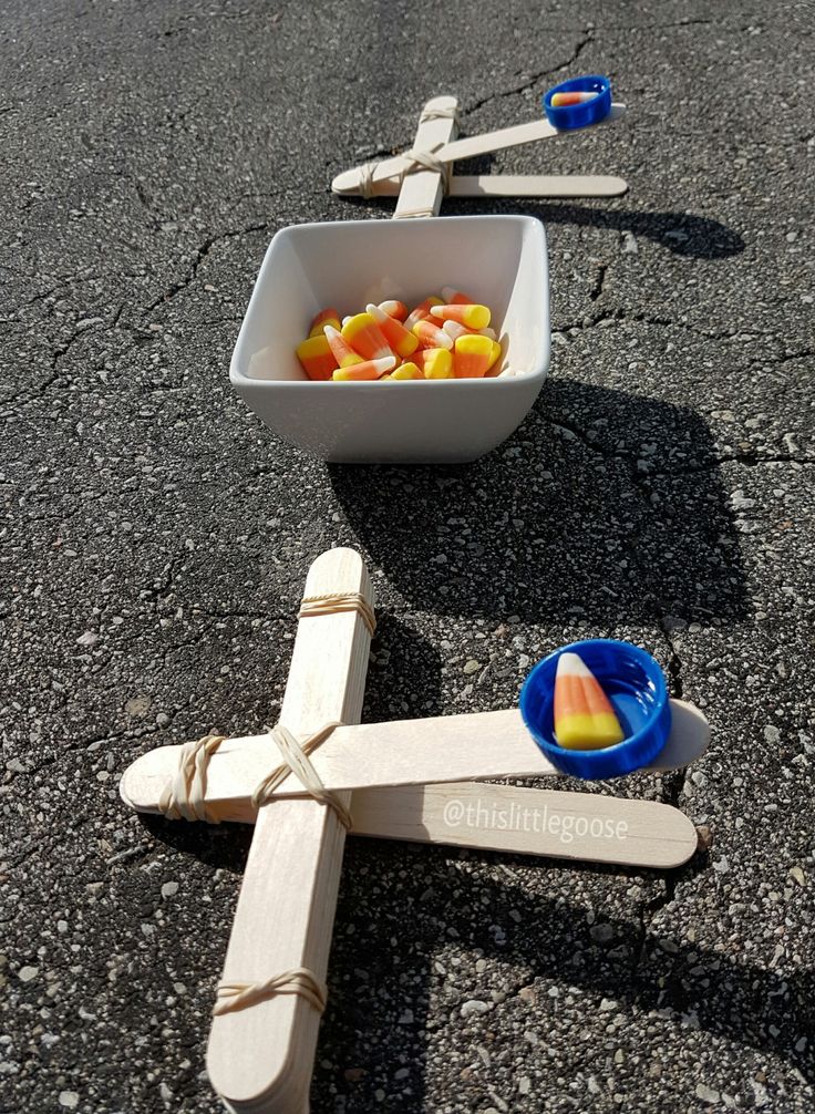 a bowl of fruit sitting on the ground next to wooden spoons