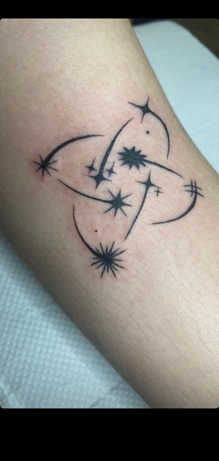 a black and white photo of a tattoo on someone's arm with stars around it