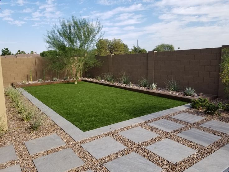 a small backyard with grass and rocks on the ground