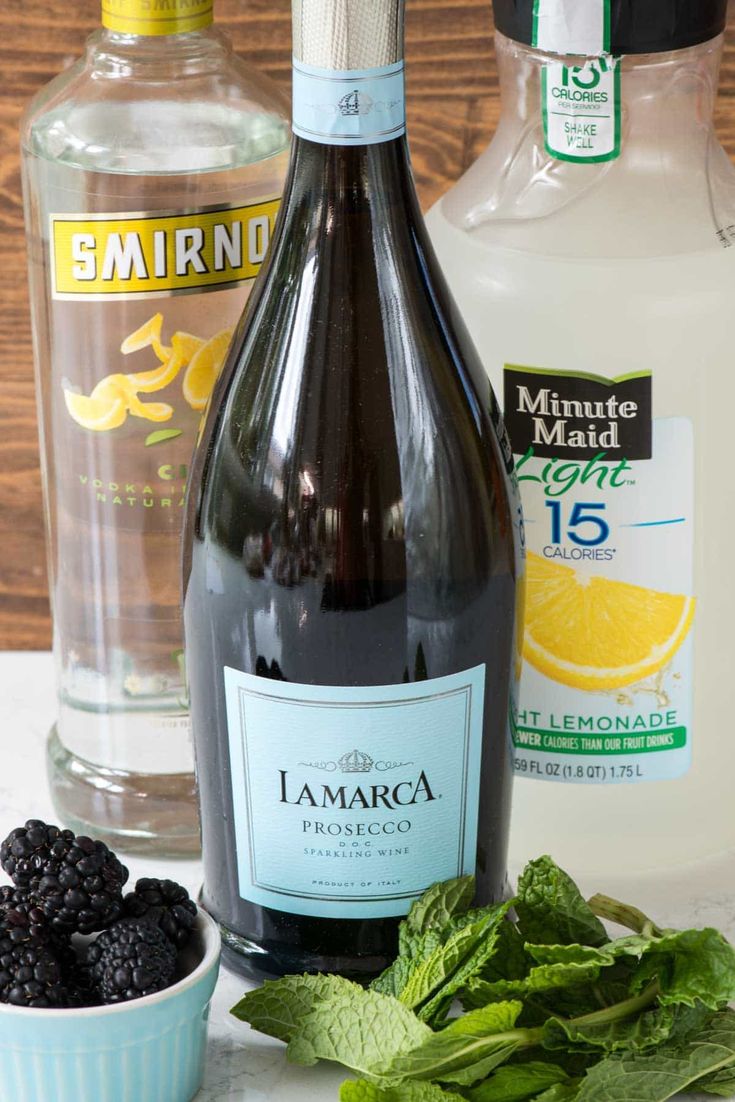 ingredients to make blackberry moscarella are displayed on a white counter top, including minty leaves and lemons