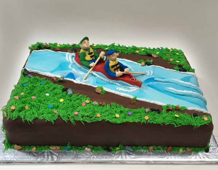 a cake with two people in a canoe on the river and grass around it,