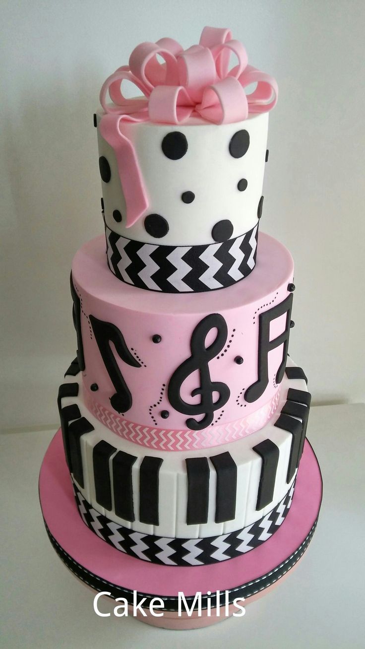 a three tiered cake decorated with musical notes and pink bow on the top layer