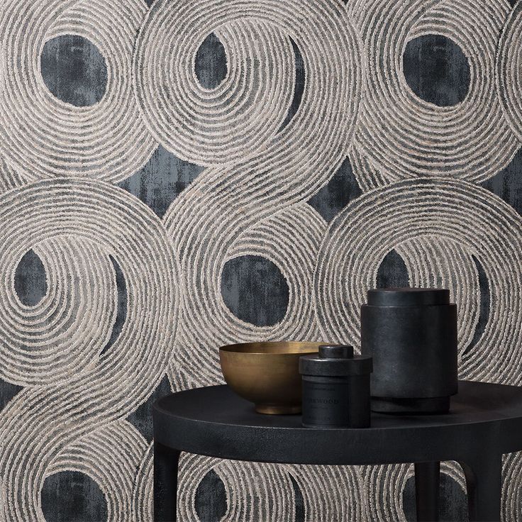 a black and white wallpaper with circles in the middle on a table next to a vase