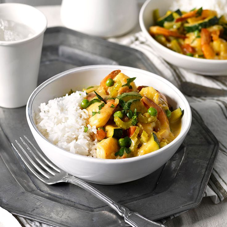 two bowls filled with food on top of a table next to white rice and silverware