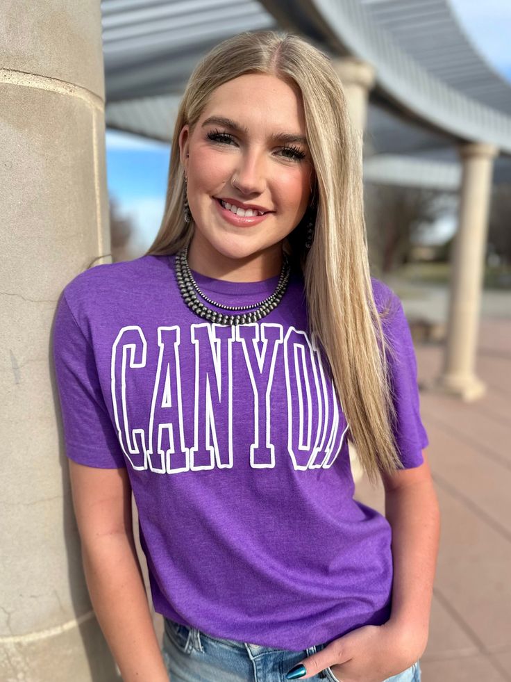 A classic tee perfect for every day wear! We love spirit tees that we can wear alone, throw a cardigan over, or wear a blazer to dress it up. This one is great for year-round and for every/any Canyon event or sport. True to size. On a gildan soft style purple tee. 60% cotton, 40% polyester. Launders well - little to no shrinkage! Available S-2XL. Trendy Purple Everyday Top, Classic Letter Print Tops For College, Trendy Crew Neck Tops For Campus, Heather Casual Tops With Letter Print, School Spirit Tops With Text Print For Campus, Casual Heather Tops With Letter Print, Campus School Spirit Tops With Text Print, Classic Everyday Tops With Text Print, Fall Campus Tops With Text Print