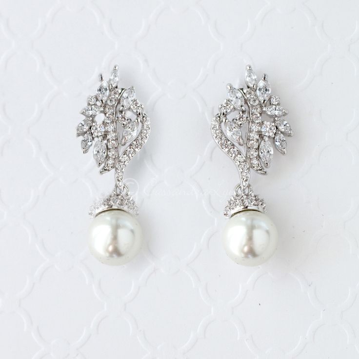 Glamorous pearl drop earrings that feature sparkling clear cubic zirconia encrusted on antique silver or gold plating with two beautiful diamond white pearl drops. These earrings are charming and elegant and will make a beautiful addition to your bridal ensemble. Pierced post backs and 1.5 inches long. Rhodium plated or gold plated, grade AAA cubic zirconia, 10mm glass pearls and lead free. Rose Gold Wedding Jewelry, Silver Bridal Earrings, Crystal Wedding Jewelry, Crystal Bridal Earrings, Pearl Earrings Wedding, Bridal Earrings Drop, Bridal Bangles, Cz Earrings, Classy Jewelry