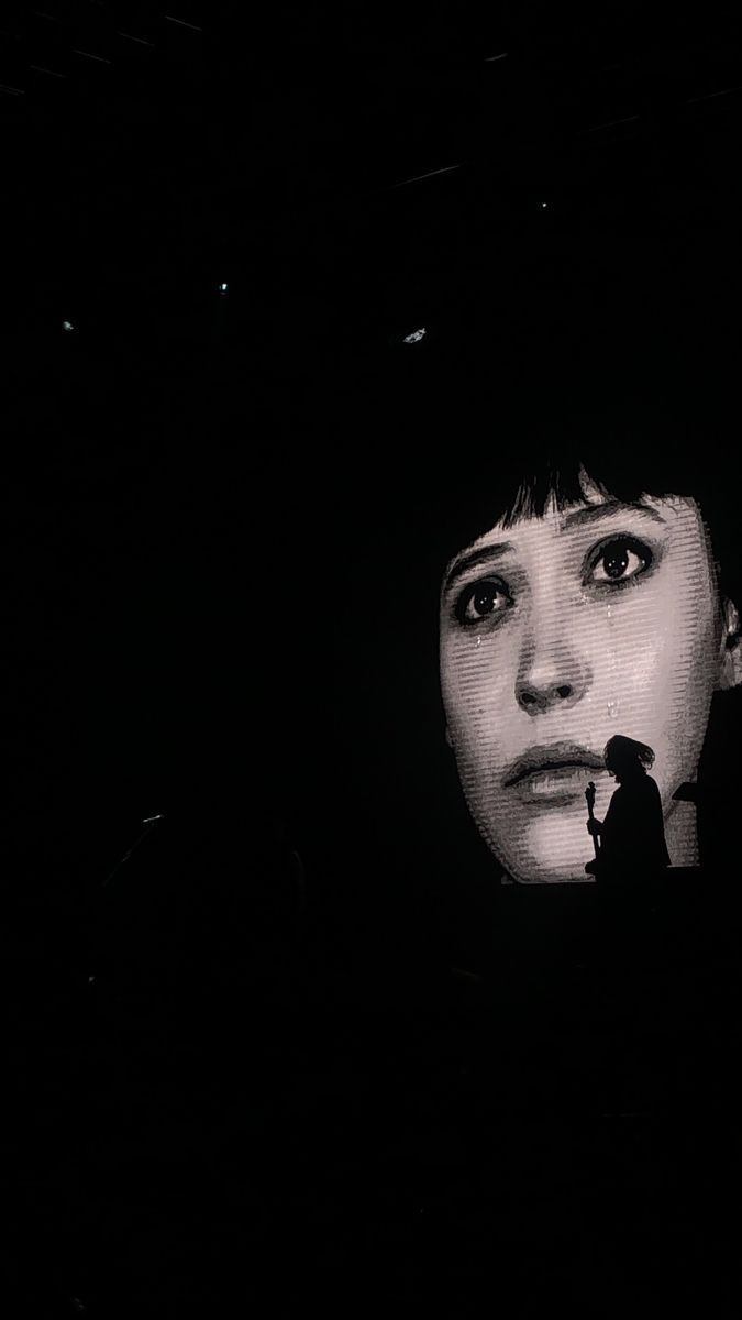 a woman is looking at the screen with her face obscured by dark lighting in front of her