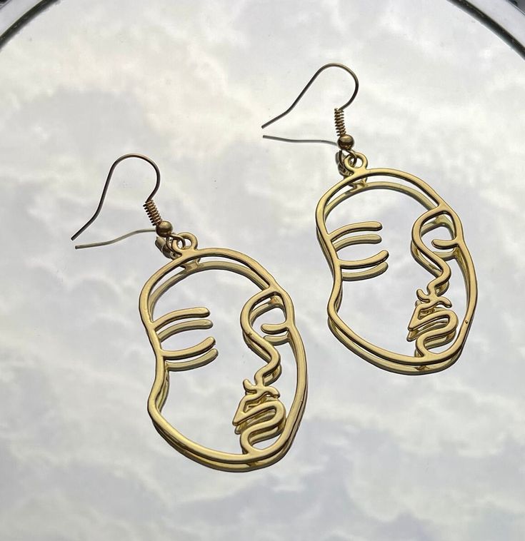 Gold Outlined Face Shaped Earring. Also available in Silver. Check out our other Face Shaped Earrings too! Artsy Gold Dangle Earrings, Gold Artsy Drop Earrings, Artsy Gold Pierced Earrings, Artsy Gold Drop Earrings, Artsy Gold Metal Earrings, Artsy Gold Nickel-free Earrings, Gold Artsy Earrings For Party, Artsy Gold Earrings For Party, Artsy Gold Earrings