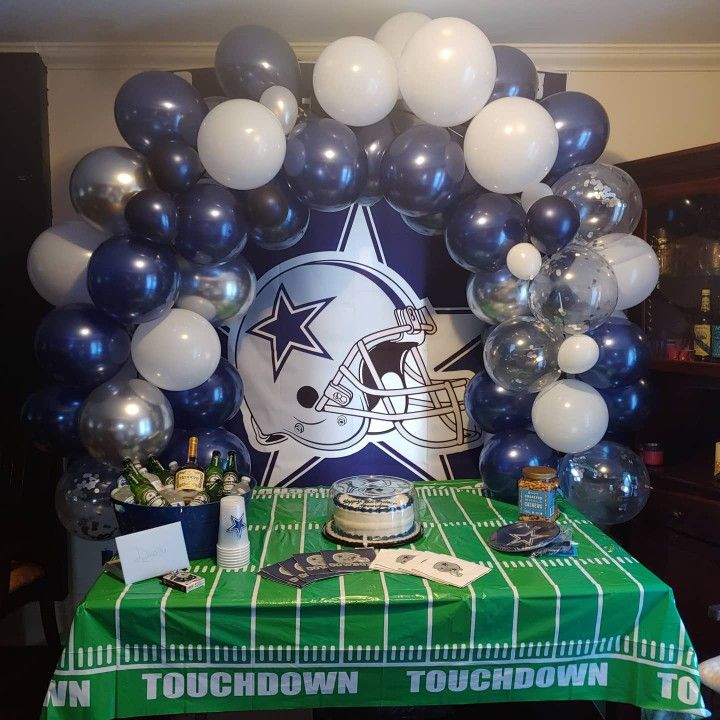 a table topped with balloons and football themed decorations on top of a green table cloth