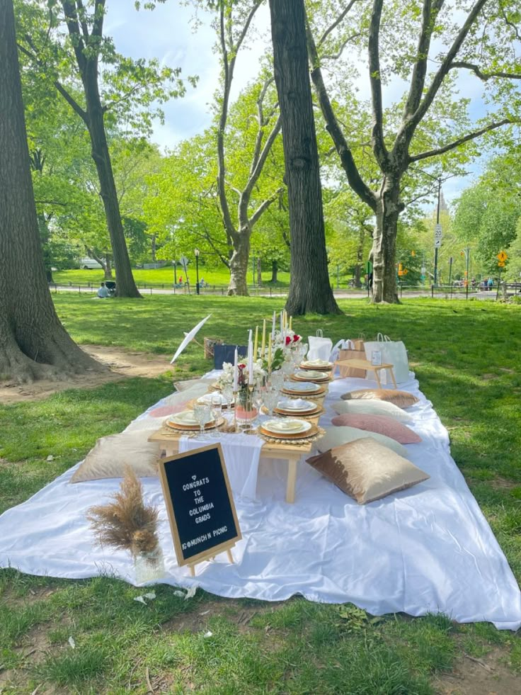 a picnic table with food and drinks on it in the middle of a grassy area