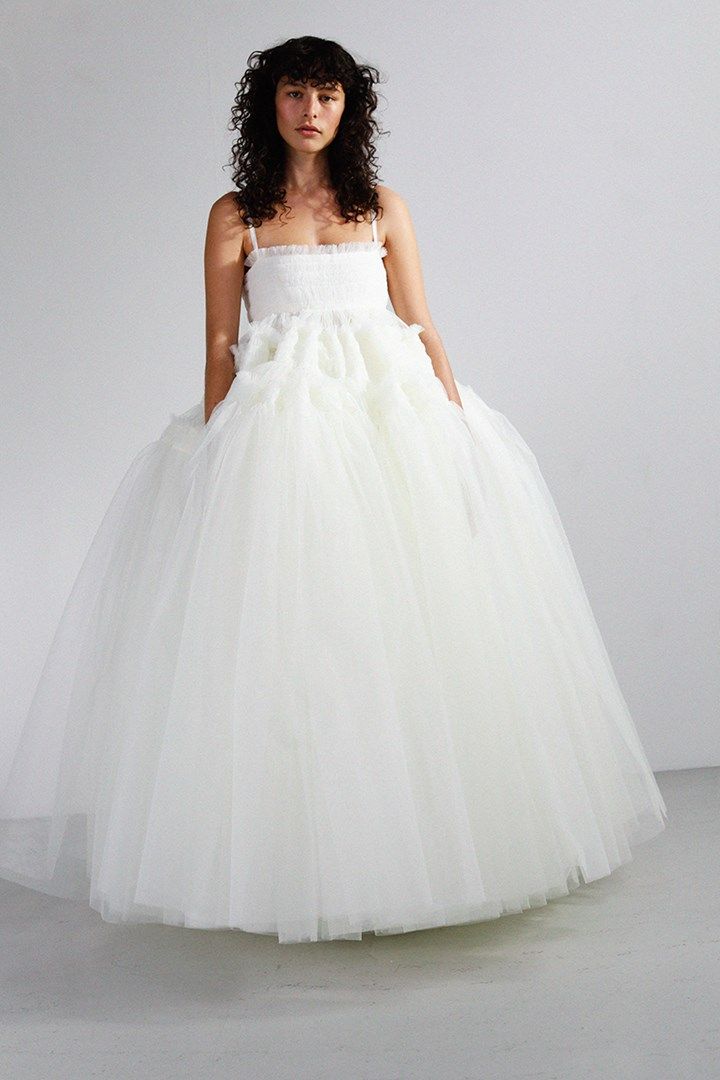 a woman in a white dress standing on a gray floor with her hands behind her back