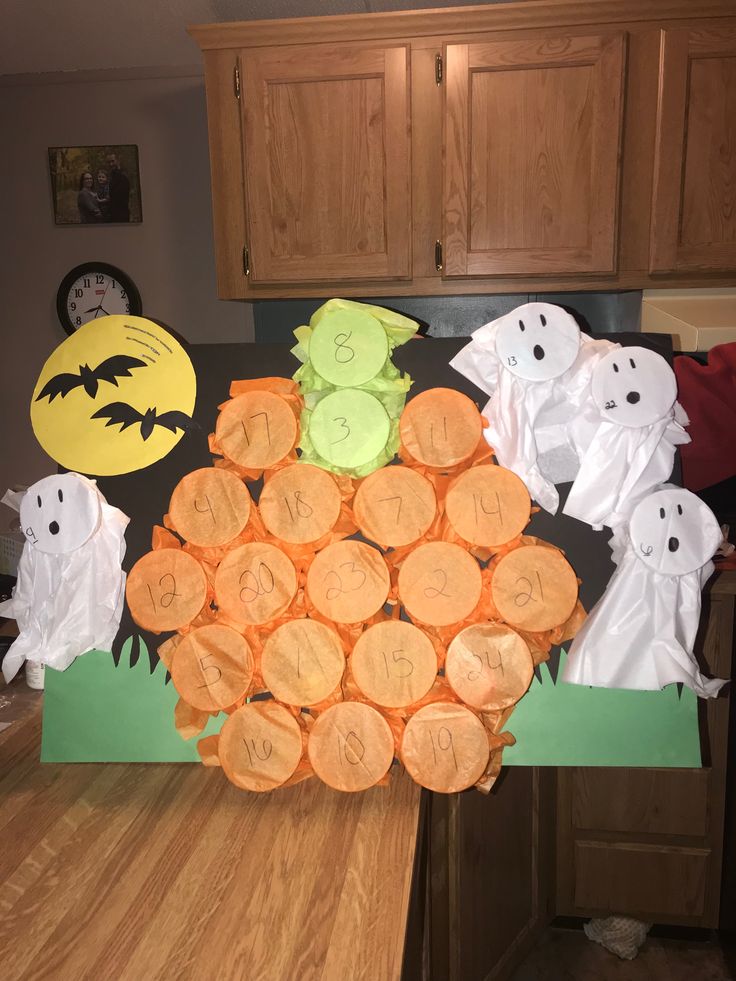 a table topped with lots of cut out pumpkins and ghost paper on top of it