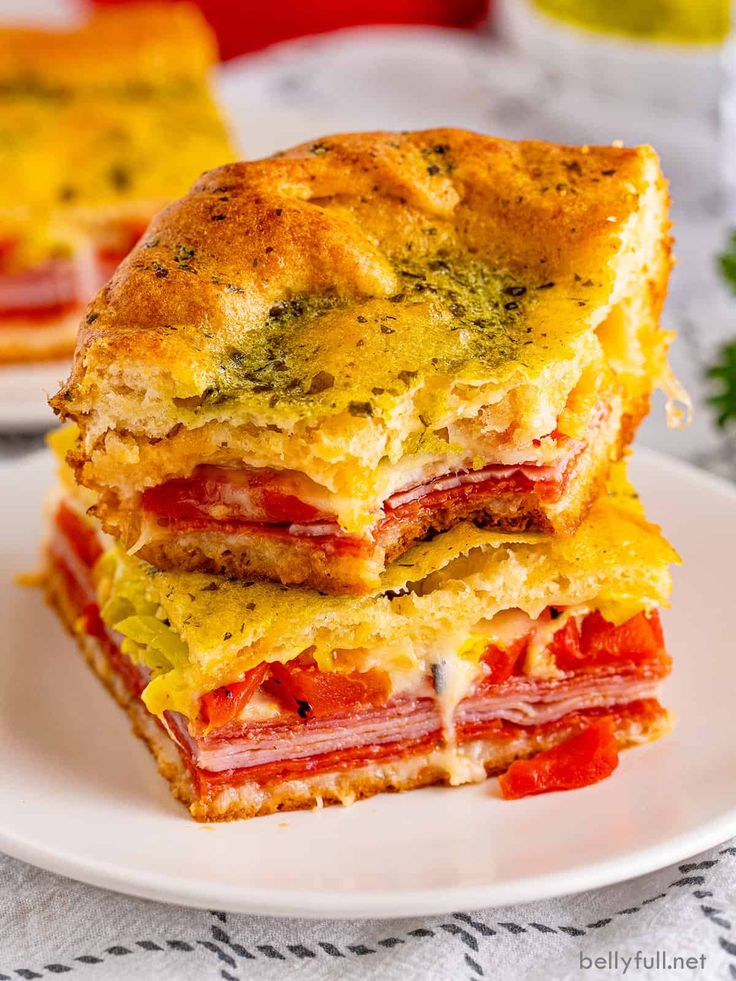 two sandwiches stacked on top of each other on a white plate with parmesan cheese