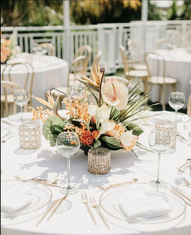 an arrangement of flowers and greenery on a table at a wedding reception with white linens