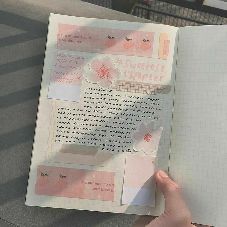 someone is holding an open notebook with stickers on it and writing in the pages