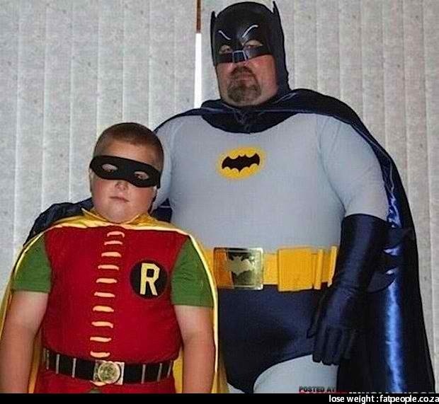 a little boy standing next to a man dressed as batman and robin wayne in costume