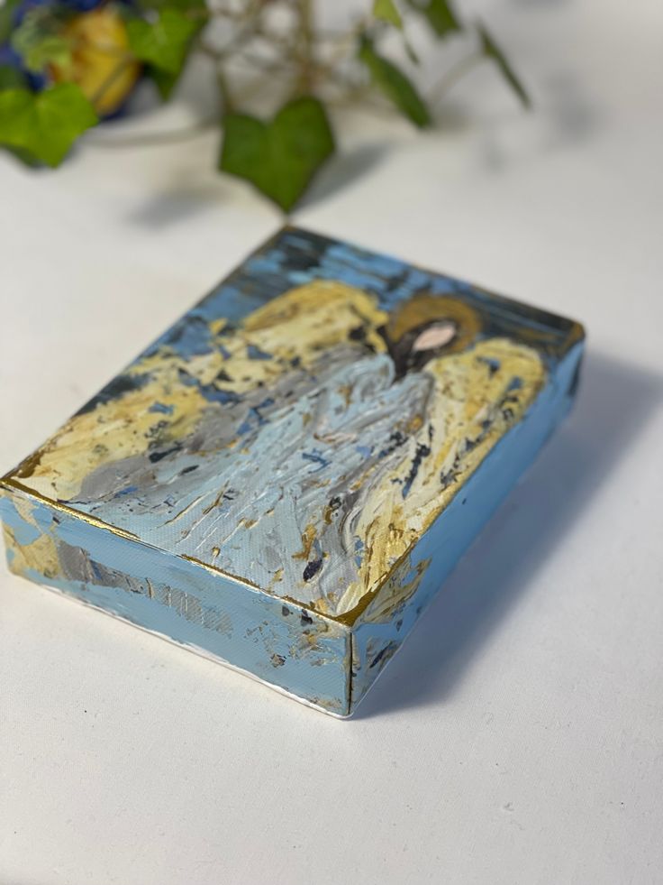 a box with a painting on it sitting next to flowers