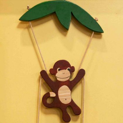 a wooden monkey hanging from a palm tree on a string with two strings attached to it