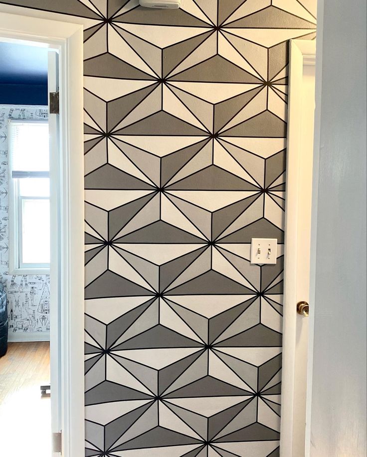 an open door leading to a bathroom with geometric wallpaper