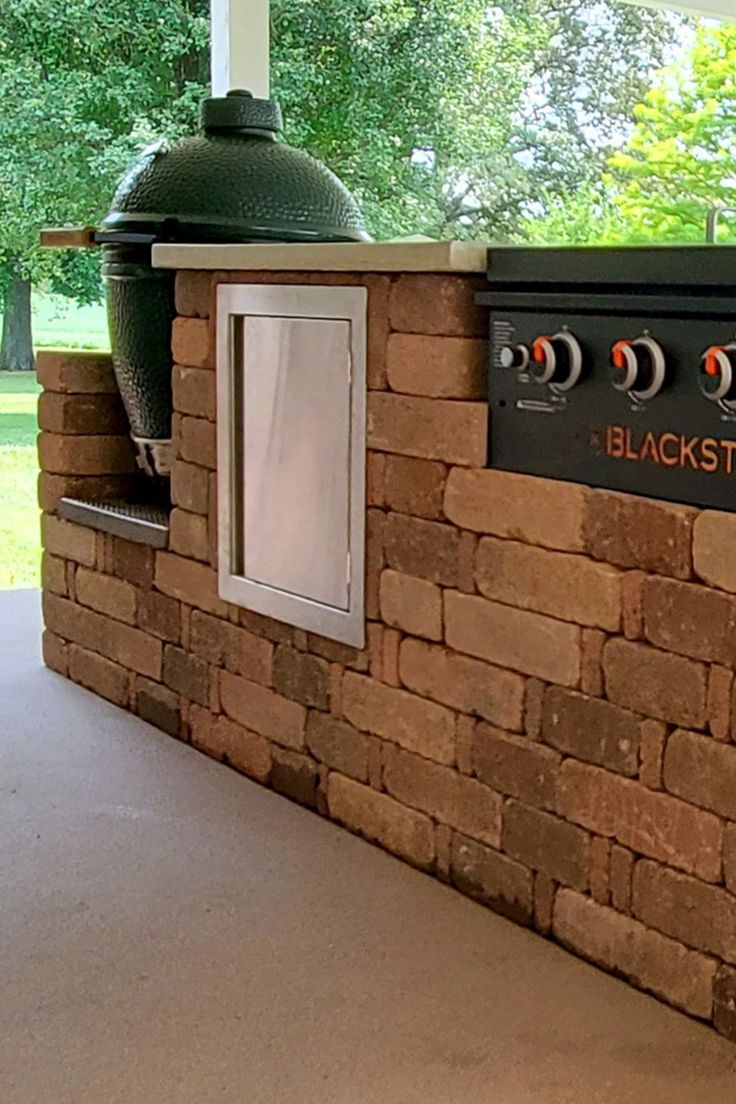 an outdoor bbq grill is built into the side of a brick wall and has a green dome on top