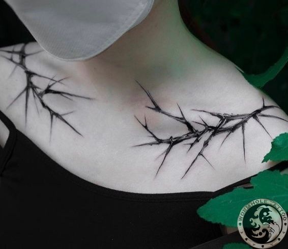 a woman's chest is covered with barbed wire and green leafy branches on it