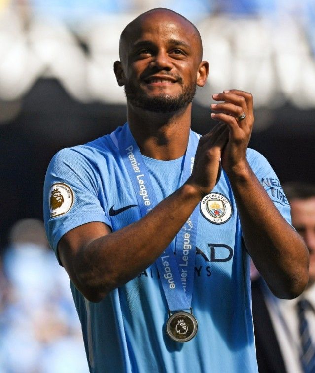 a soccer player is applauding with his hands in the air and smiling at the camera