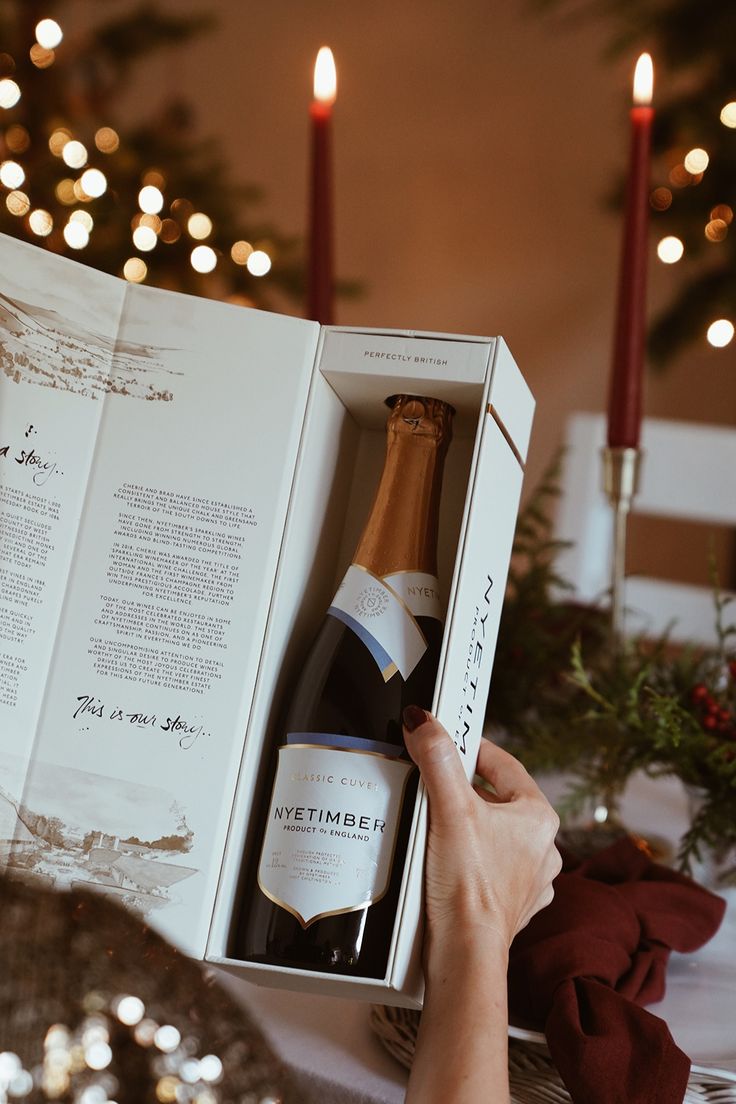 a person opening a wine bottle in a box on top of a table with candles